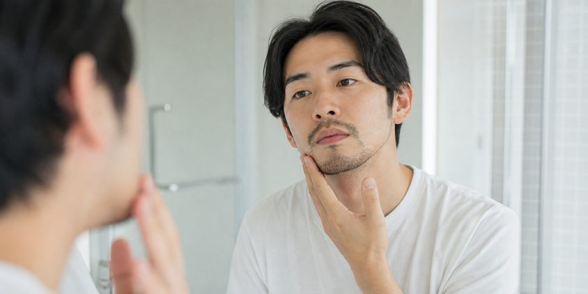 鏡でヒゲの状態を確認する男性（回数や効果には個人差があるイメージ）