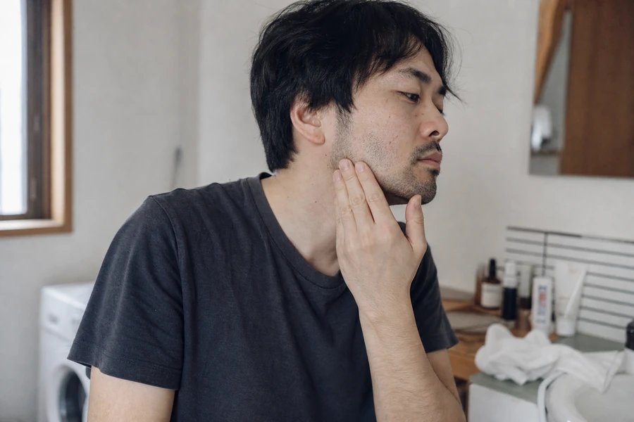 朝の洗面所でヒゲの状態を確認する男性