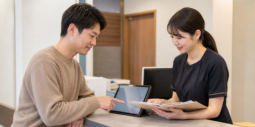 ヒゲ脱毛の予約変更条件を受付で確認する男性