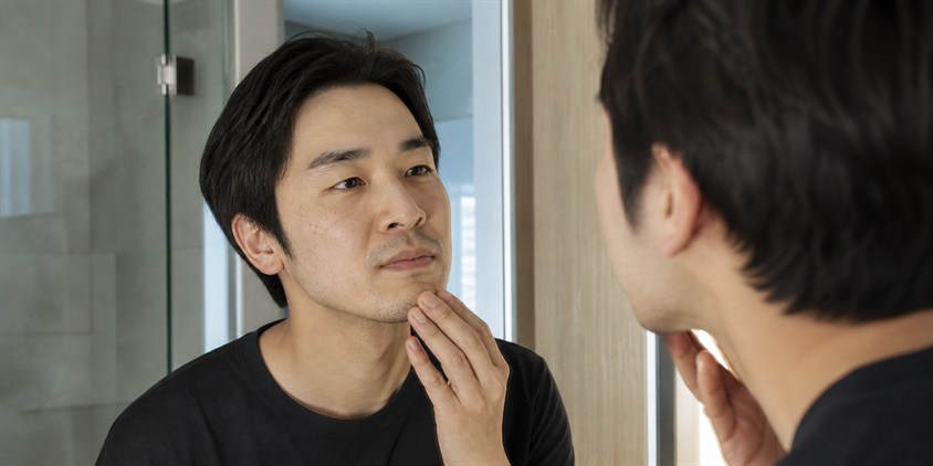ヒゲ脱毛後の毛量を鏡で確認する男性